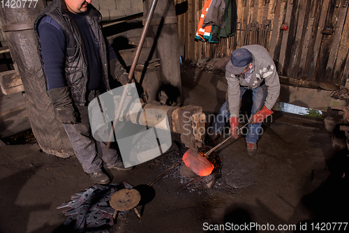 Image of blacksmith workers using mechanical hammer at workshop