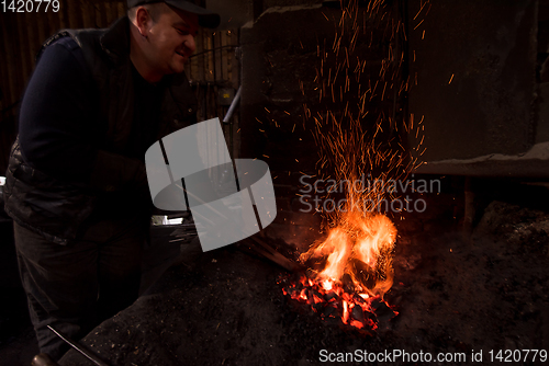 Image of young traditional Blacksmith working with open fire