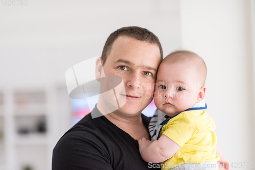 Image of young father holding baby near the window at home