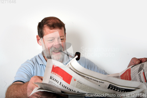 Image of Mature scandinavian man smoking  pipe and reading news