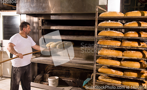 Image of bakery worker taking out freshly baked breads