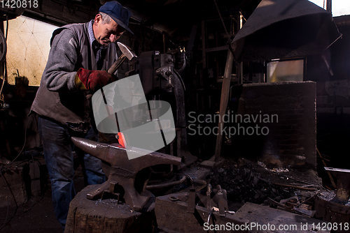 Image of blacksmith manually forging the molten metal