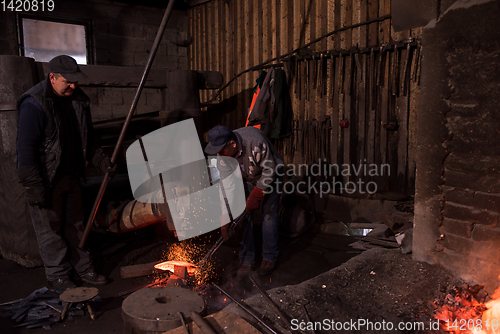 Image of blacksmith workers using mechanical hammer at workshop