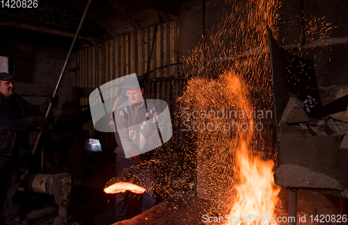 Image of blacksmith workers using mechanical hammer at workshop