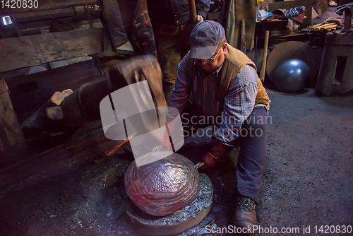 Image of blacksmith workers using mechanical hammer at workshop