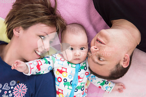 Image of Top view of smiling young couple lying with their baby