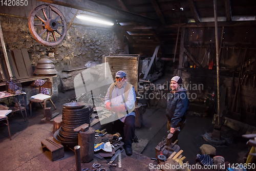 Image of portrait of two generations traditional blacksmith