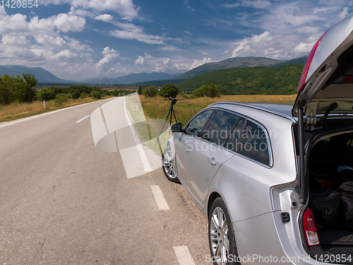 Image of profesional DSLR camera on a tripod at asphalt road in beautiful