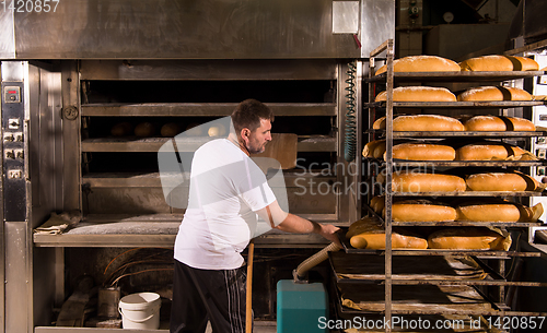 Image of bakery worker taking out freshly baked breads