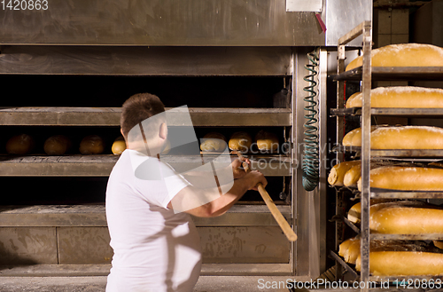 Image of bakery worker taking out freshly baked breads