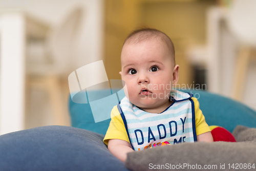 Image of baby boy sitting between the pillows on sofa