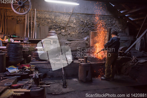 Image of young traditional Blacksmith working with open fire