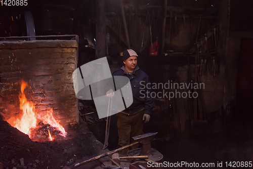 Image of young traditional Blacksmith working with open fire