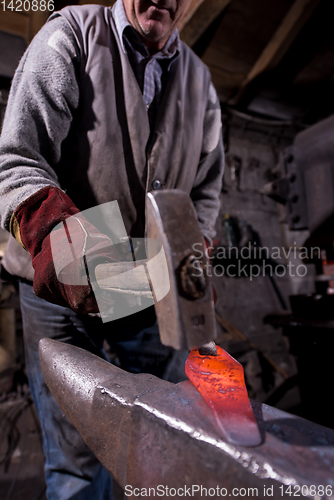 Image of blacksmith manually forging the molten metal