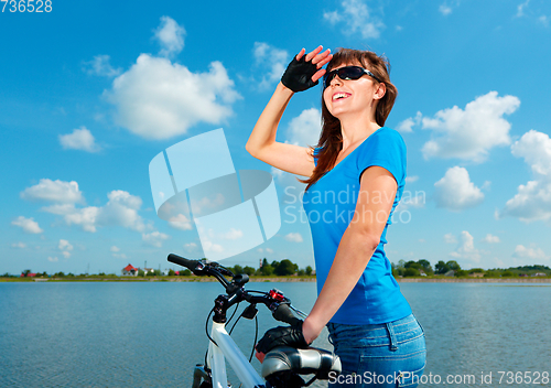 Image of Young woman is standing behind of her bicycle