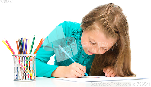 Image of Little girl is drawing using pencils