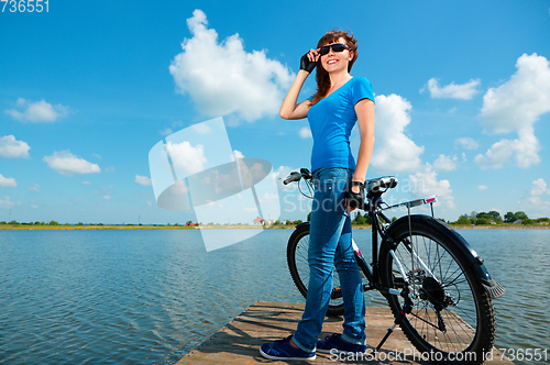 Image of Young woman is standing in front of her bicycle