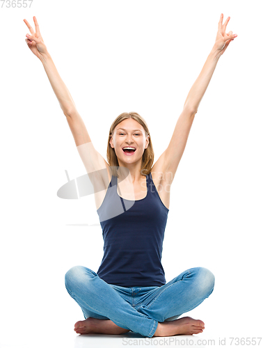 Image of Young happy woman is sitting on the floor