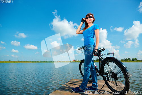 Image of Young woman is standing in front of her bicycle