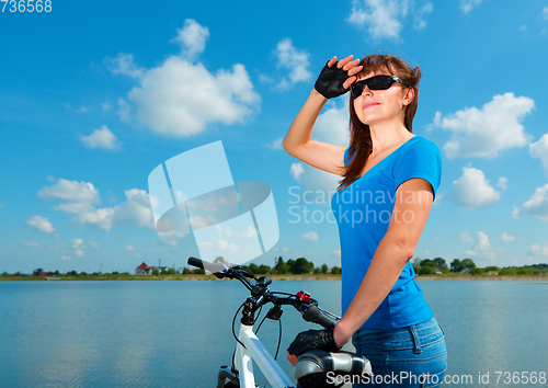 Image of Young woman is standing behind of her bicycle