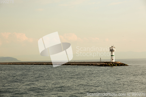 Image of Beautiful seascape with lighthouse. Calm sea and a lighthouse on the pier. Small beacon in the endless sea. Landscape and beacon. Lighthouse