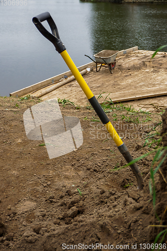 Image of Wheelbarrow and shovel for construction in site building area.