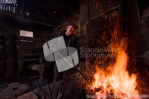 Image of young traditional Blacksmith working with open fire