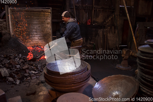 Image of young traditional Blacksmith working with open fire