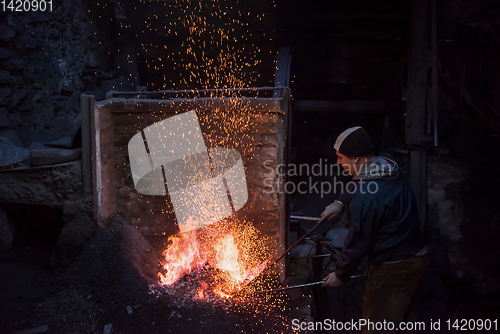 Image of young traditional Blacksmith working with open fire