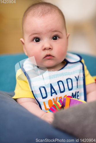 Image of baby boy sitting between the pillows on sofa