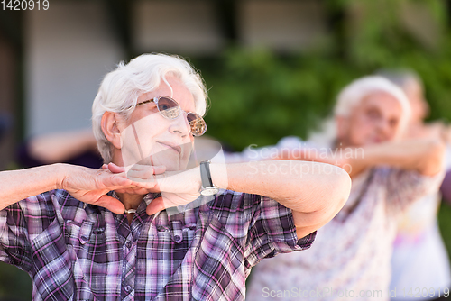 Image of senior woman exercising with friends