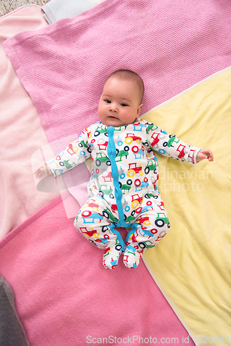 Image of top view of newborn baby boy lying on colorful blankets