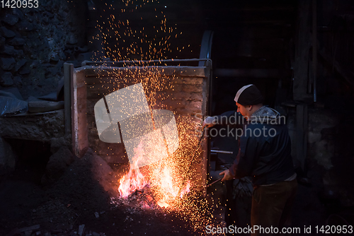 Image of young traditional Blacksmith working with open fire