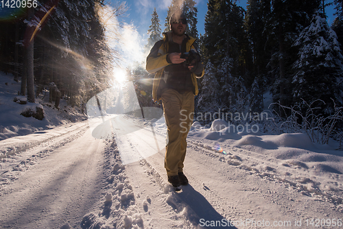 Image of young photographer walking on snowy country road