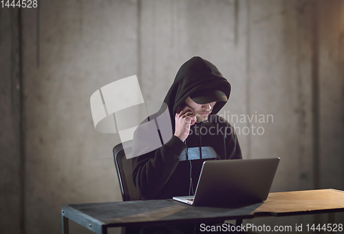 Image of talented hacker using laptop computer while working in dark offi