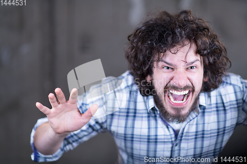 Image of casual businessman screaming in front of a concrete wall