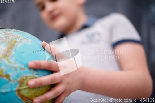 Image of boy using globe of earth in front of chalkboard