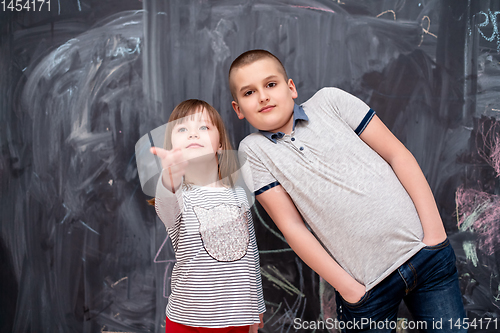 Image of boy and little girl standing in front of chalkboard