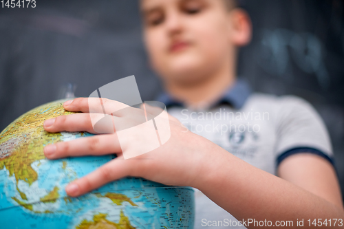 Image of boy using globe of earth in front of chalkboard