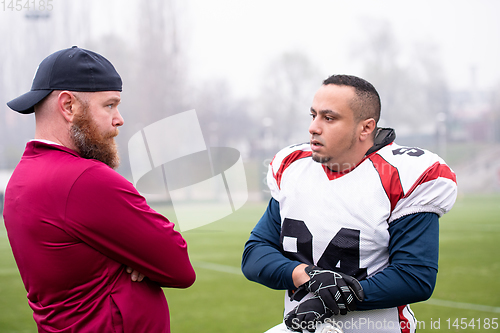 Image of american football player discussing strategy with coach