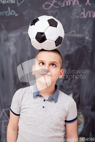 Image of happy boy holding a soccer ball on his head