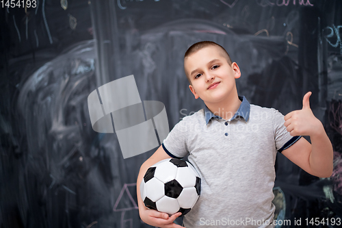 Image of happy boy holding a soccer ball in front of chalkboard