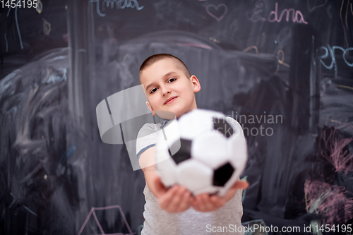 Image of happy boy holding a soccer ball in front of chalkboard