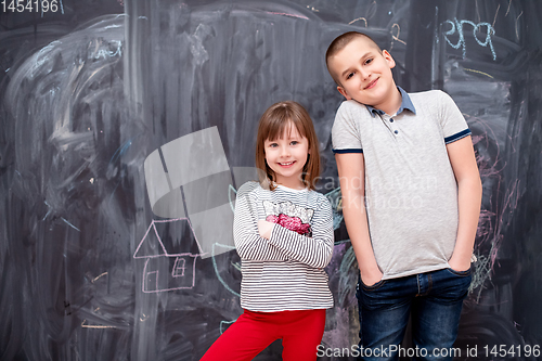 Image of boy and little girl standing in front of chalkboard