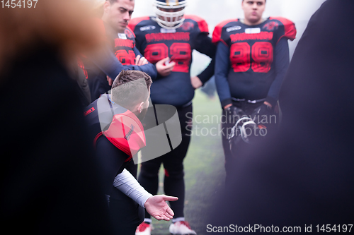 Image of american football player discussing strategy with his team