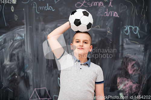 Image of happy boy holding a soccer ball on his head