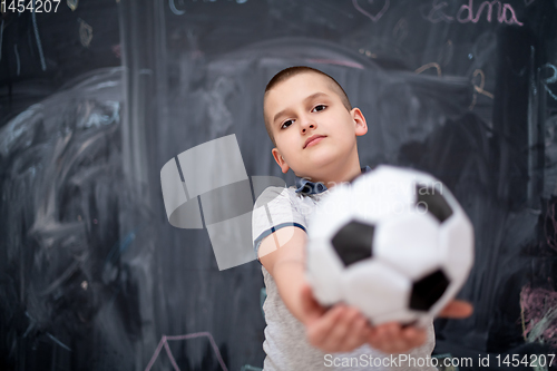 Image of happy boy holding a soccer ball in front of chalkboard