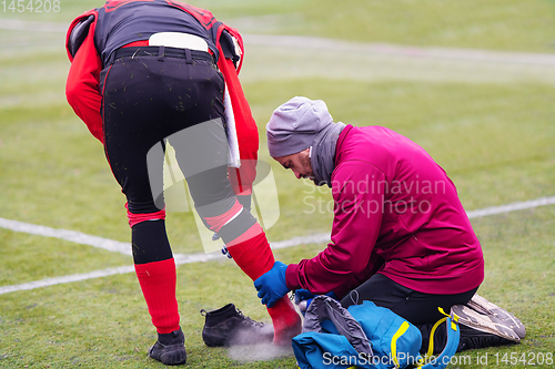 Image of Sports doctor using freezing spray while treating injured sportm