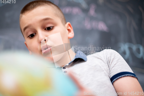 Image of boy using globe of earth in front of chalkboard