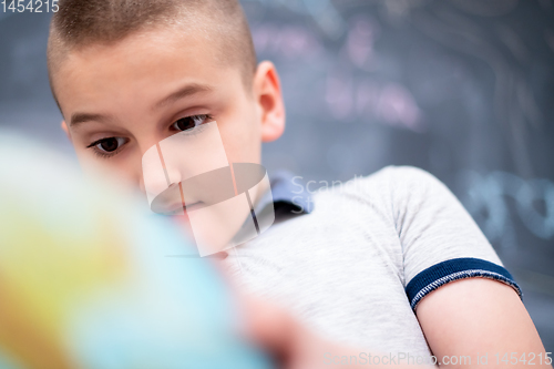 Image of boy using globe of earth in front of chalkboard